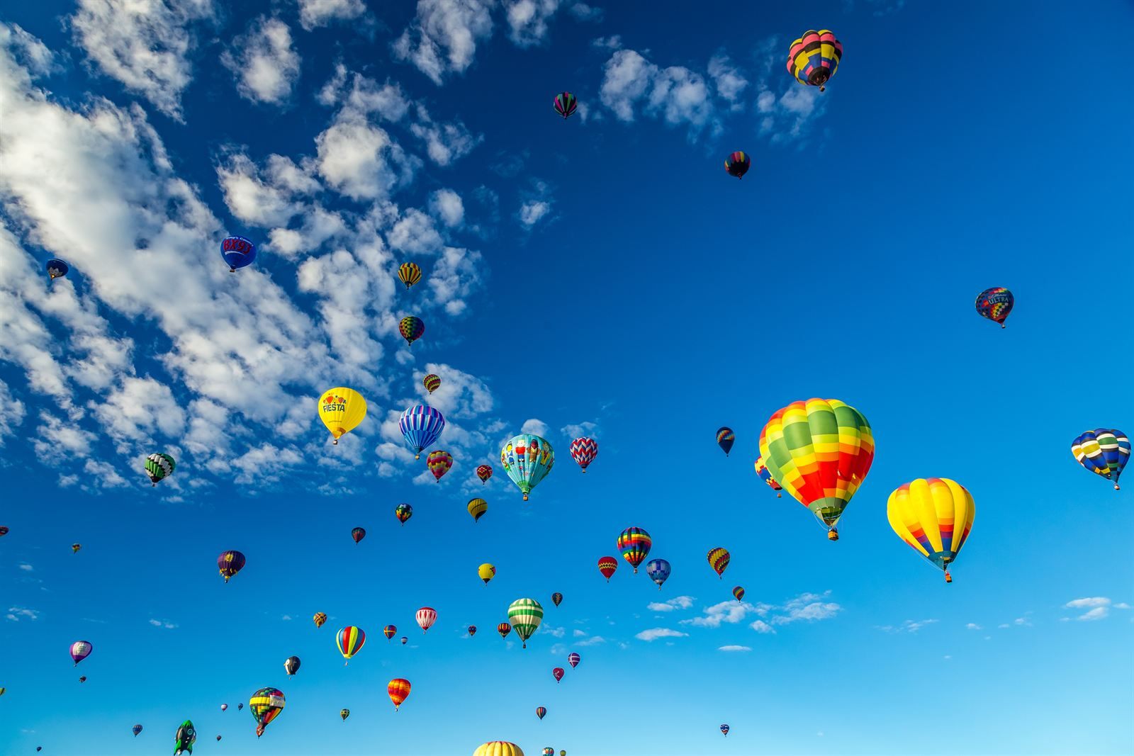 Colorful hot-air balloons floating in a deep blue sky with white clouds