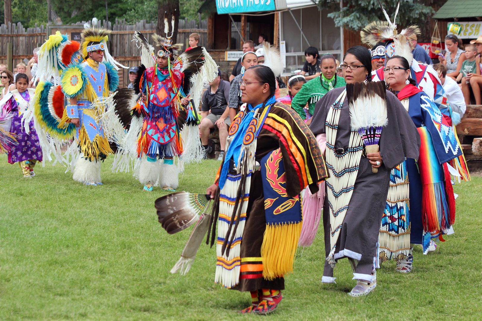 Dancers in Native American regalia with feathers and fringe at an outdoor powwow