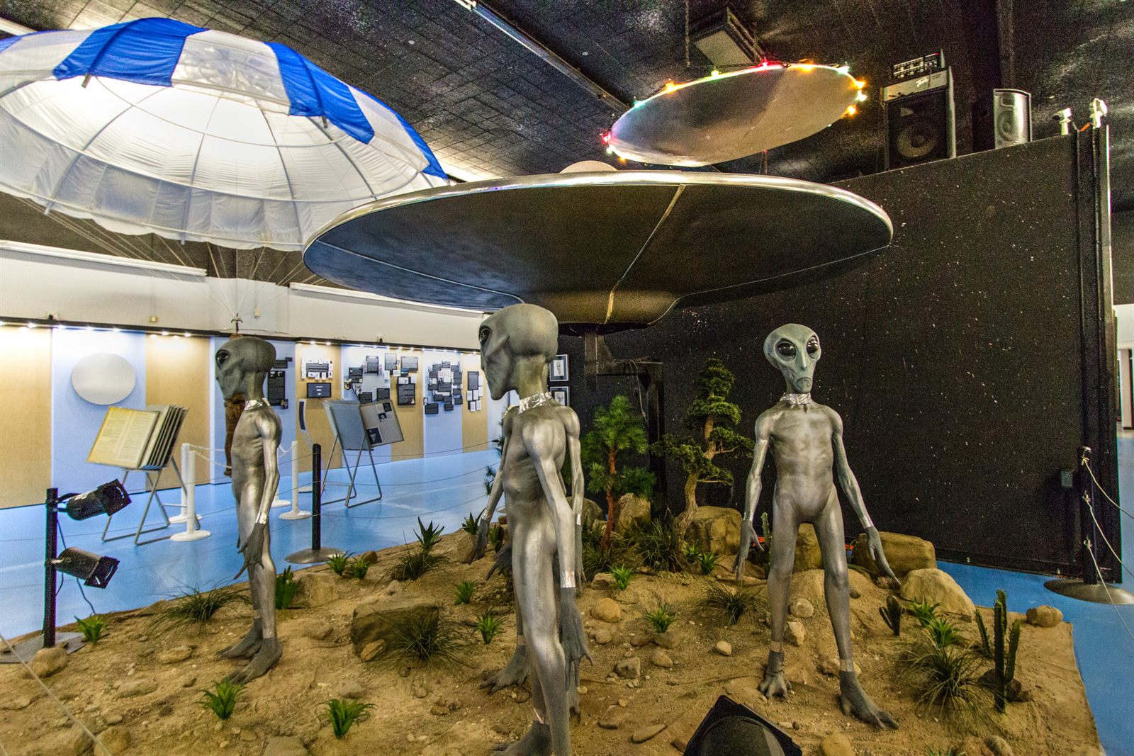 Gray alien figures beneath a model flying saucer in a UFO museum exhibit